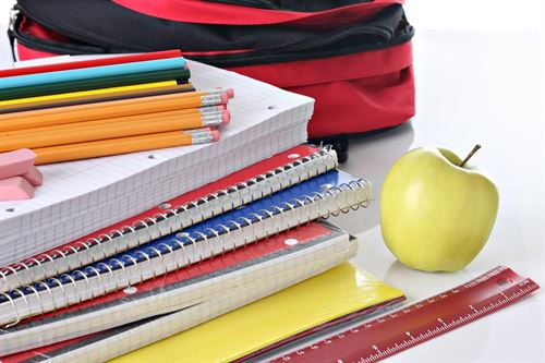 stack of notebooks and pencils with apple, ruler and bag